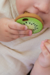 Baby clutching and chewing the Oli & Carol Jose Antonio The Kiwi Mini Baby Teether