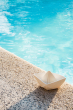 Oli & Carol White natural rubber Origami Boat bath toy pictured on the side of a pool 