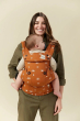 Front view of a woman carrying her baby on her front in the Tula Ergonomic Multi-Position Explore Baby Carrier 7-45lbs in Sedonia. 