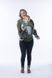Woman stood on a white background carrying a baby on her front in the Tula explore baby carrier