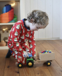 Child wearing Maxomorra Swedish Santa Pyjamas, playing with a tractor and trailer filled with beads