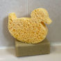 A Slice of Green plastic-free cellulose duck shape sponge on top of a green soap bar