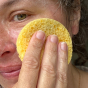 Close up of woman exfoliating her face with the A Slice of Green cellulose facial sponge