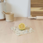 Slice of lemon on top of a small Abeego reusable food wrap on a kitchen counter