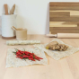 Ginger and chillis laid out on some Abeego reusable natural beeswax food wraps on a wooden worktop