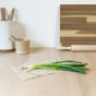 Spring onions laid out on an Abeego beeswax food wrap on a wooden counter