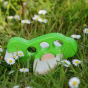 A Bajo airplane in a green colour placed on grass outdoors surrounded by daisies
