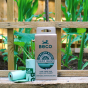 Beco Pets plant based dog poop bags on a wooden fence in front of some green plants