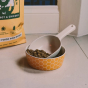 Beco Pets natural bamboo pet food scoop in a biscuit bowl on a kitchen floor.