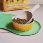 Beco Pets sustainable bamboo food bowl on top of green silicone placemat in a white kitchen floor.