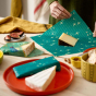 Close up of hands wrapping up some cheese in a reusable beeswax food wrap sheet from the beeswax wrap company on a wooden table