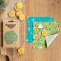 The Beeswax Wrap Co natural beeswax pennies on a wooden board next to some reusable food wraps