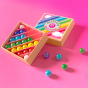 Billes & Co childrens recycled glass mini rainbow marbles set on a pink background with some coloured marbles scattered around the box
