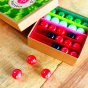 Billes & Co childrens recycled glass watermelon marbles mini set open on a wooden worktop with 3 red marbles scattered around the box