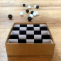 Billes & Co recycled glass marbles set on a wooden worktop, with black and white marbles scattered around the box