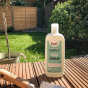 Bio-D Home & Garden Vegan Cleaner in a refillable 750ml bottle, on a wooden decking outside in a garden