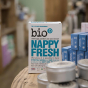 Bio-D box of nappy fresh powder 500g on a wooden table, with an out of focus tin and blue box 