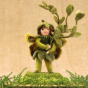 The Makerss Needle Felt Box Fairy. A beautifully crafted needle felt fairy in green,  holding a green stem of leaves and stood on a green base with a sandy coloured background