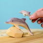 Bumbu Wooden Dolphin.  The toy is paired with a baby dolphin and an adult hand is shown for scale.