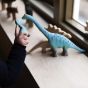 A child playing with the Bumbu Brontosaurus toys on a window sill  