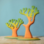 Bumbu small and big dino trees pictured placed on a wooden surface in front of a blue wall