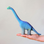 The Bumbu Big Wooden Brontosaurus pictured in an adult's hand