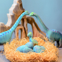 A Jurassic Play Scene with two Large Brontosaurus Dinosaurs watching over their nest of eggs, and a baby Brontosaurus sat patiently waiting for the eggs to hatch