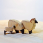 Bumbu plastic free handmade mini wooden lamb toy stood next to two other wooden Bumbu sheep figures on a light wooden background