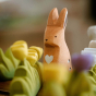 Close up of a Bumbu handmade miniature wooden Bunny next to a Bumbu large grass toy with yellow flowers