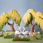 Bumbu plastic-free wooden swan figures on a blue and green background next to some large wooden grass and willow tree toys