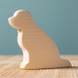 Bumbu Wooden Dog - Paint Your Own. The toy sits on a wooden surface against a blue background.