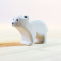 Bumbu eco-friendly small wooden standing polar bear animal figure stood on a light wooden worktop in front of a white background
