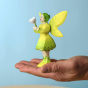 The Bumbu Woodland Fairy is stood on the palm of a person with a blue background
