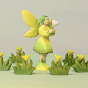 Bumbu Woodland Fairy holding a small Bumbu white wooden flower in their hands, stood among Bumbu Grass with Yellow flowers and a pale green background