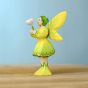 Bumbu Woodland Fairy holding a small Bumbu white wooden flower in their hands, with a light blue background and stood on a light brown wooden table