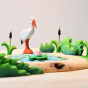 Close up of the Bumbu small green shrub toys on a Bumbu wooden lake puzzle next to a large white bird figure