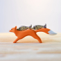 Close up of the Bumbu plastic free handmade running fox figure with two wooden fish toys balanced on its back in front of a white background
