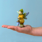 Bumbu Wooden Winged Elf. A whimsical and playful hand painted and hand crafted wooden elf with a painted green hat, blue and green wings, yellow and green outfit and light shoe details, stood on a persons palm and a light blue background