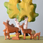 Bumbu plastic-free wooden stag toy stood next to a group of wooden deer and fawn toys on a green worktop