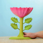 The Large Pink Flower by Bumbu is an impressive wooden flower with four leaves and a rich pink bloom, it stands on a green wooden base, with a blue background. An adults hand is shown for scale.