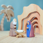 Bumbu Handmade Wooden Mary Figure kneeling down and looking down on the Bumbu Jesus and crib. Mary is kneeling next to the Wooden Joseph figure.