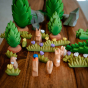 Bumbu children's wooden grass toys laid out on a wooden table in a small world scene with toy rabbits and green trees