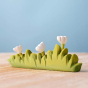 Bumbu handmade wooden large grass with white flowers toy on a wooden worktop in front of a blue background