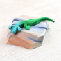 Bumbu hand carved wooden toy lizard on a mini wooden rock on a beige background