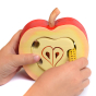 Close up of hands threading a wooden worm toy through the Bumbu eco-friendly slotting apple toy on a white background