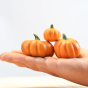 Close up of a hand holding the Bumbu 3 wooden pumpkin children's food toys in front of a white background