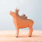 Bumbu eco-friendly wooden stag toy figure stood on a wooden worktop in front of a blue background