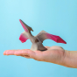 Bumbu Wooden Pteranodon Dinosaur. The toy sits on an adult's hand against a blue background.