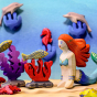 Bumbu wooden Mermaid toy figure posed in an aquatic ocean scene with Bumbu fish, dolphin, and coral.