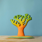 Bumbu Small Dino Tree pictured on a wooden surface with a blue background  